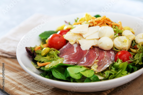 Salad with fusilli pasta accompanied tomatoes, mozzarella, smoked ham and italian cheese