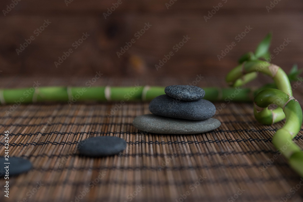 Φωτογραφία Pyramids of gray zen pebble meditation stones with green bamboo leaves and on wooden background
