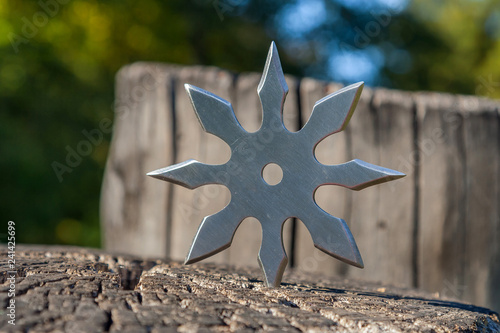 Shuriken (throwing star), traditional japanese ninja cold weapon stuck in wooden background