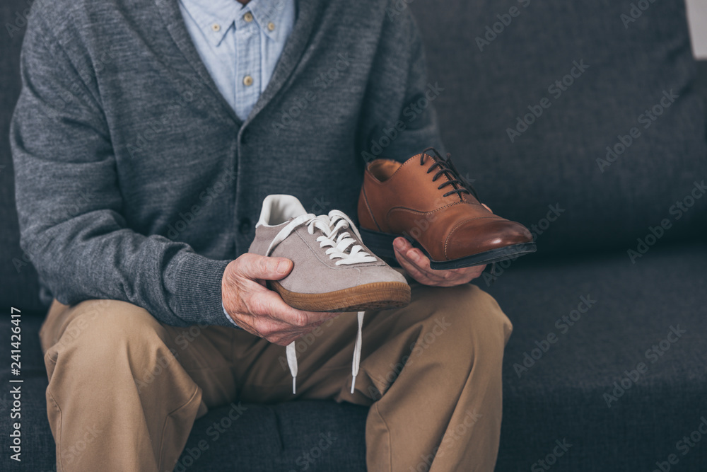 cropped view of senior man holding classic and modern shoes in hands  Stock-bilde | Adobe Stock
