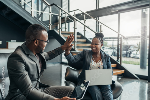 Two friendly smiling african business people celerbarting their sucess with a high five