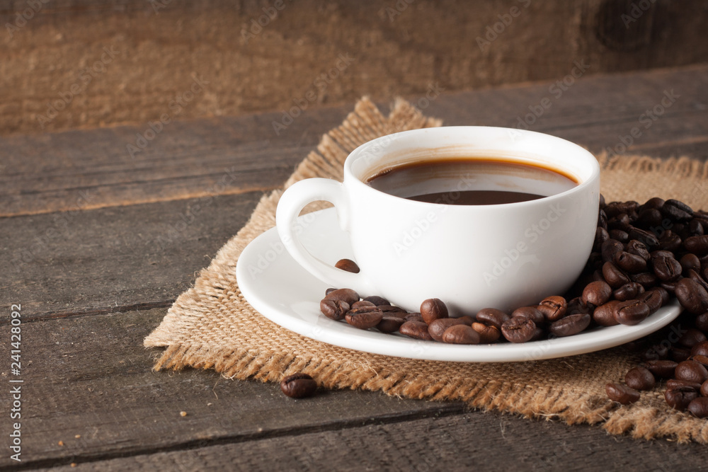 Coffee cup and beans on a rustic background. Coffee Espresso and a piece of cake with a curl. Cup of Coffee and coffee beans on table. Coffee cup and beans on a rustic background. Coffee Espresso and a piece of cake with a curl. Cup of Coffee and coffee beans on table.
