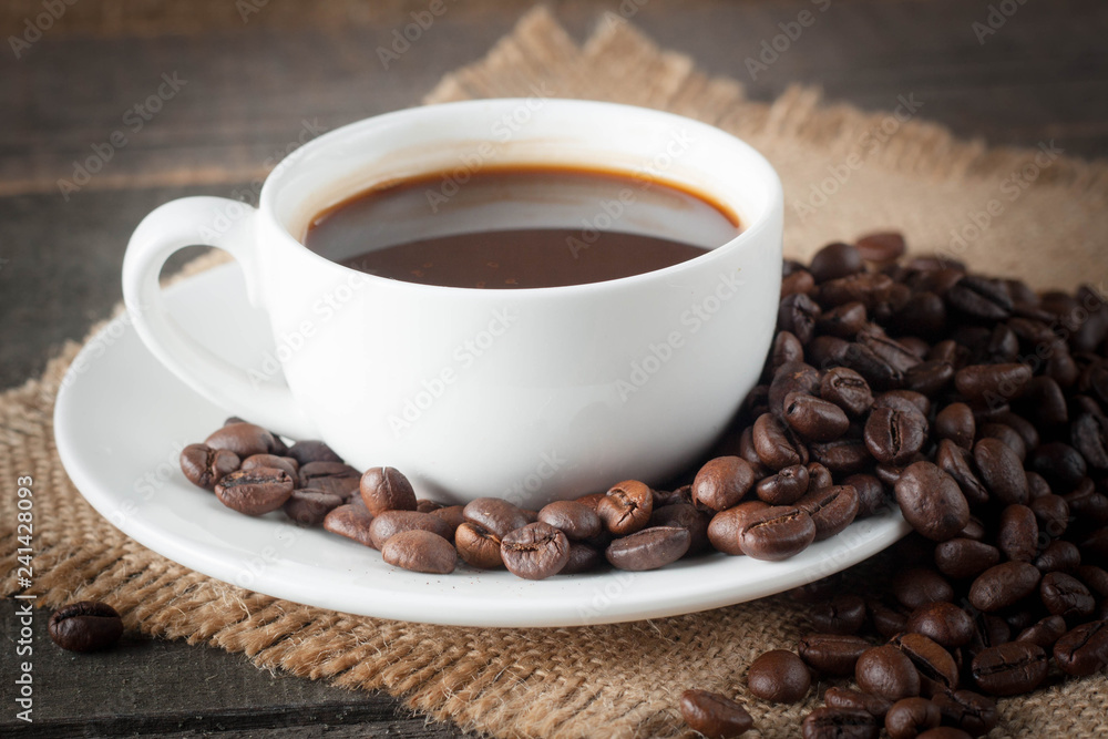 Coffee cup and beans on a rustic background. Coffee Espresso and a piece of cake with a curl. Cup of Coffee and coffee beans on table. Coffee cup and beans on a rustic background. Coffee Espresso and a piece of cake with a curl. Cup of Coffee and coffee beans on table.