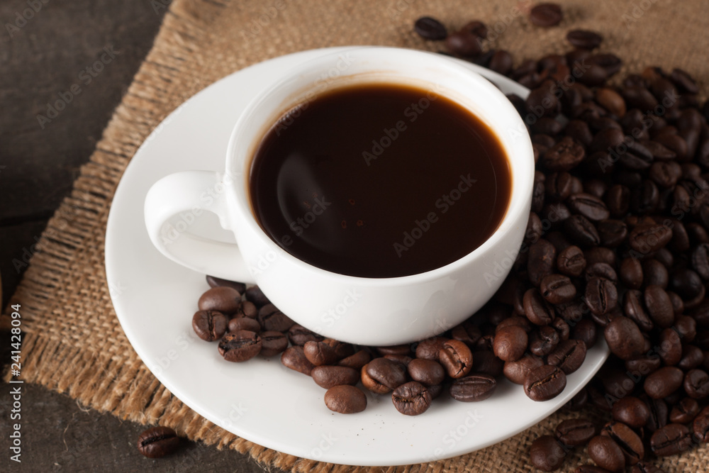 Coffee cup and beans on a rustic background. Coffee Espresso and a piece of cake with a curl. Cup of Coffee and coffee beans on table. Coffee cup and beans on a rustic background. Coffee Espresso and a piece of cake with a curl. Cup of Coffee and coffee beans on table.