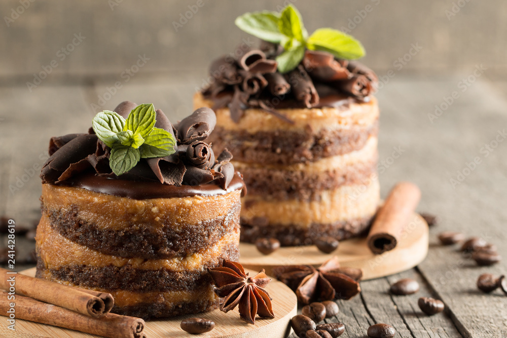 Dark chocolate cakes on black slattern board with mint, cinnamon, coffee beans on a wooden background. Tasty dessert food concept. Dark chocolate cakes on black slattern board with mint, cinnamon, coffee beans on a wooden background. Tasty dessert food concept.