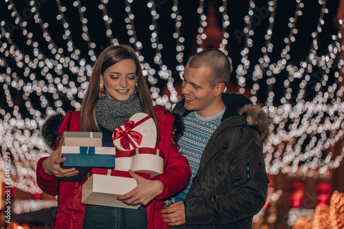 Young couple holding presents in a box and having fun at night
