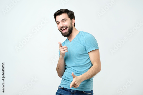 Portrait of happy hispanic man with beard pointing at you.