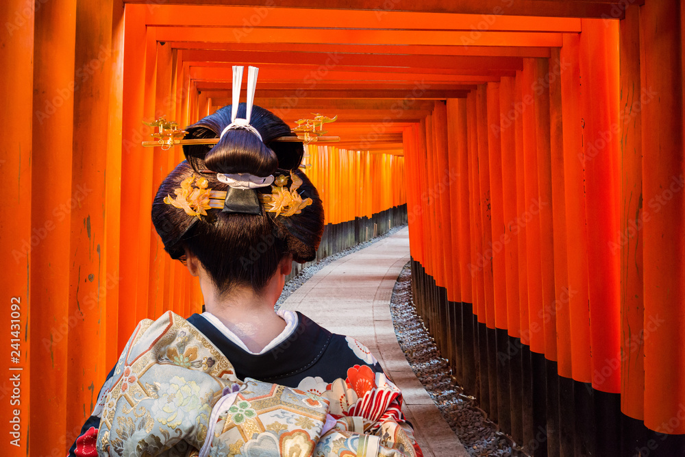 Naklejka premium Kobieta w tradycyjnym kimonie chodzenie na torii bramy, Japonia