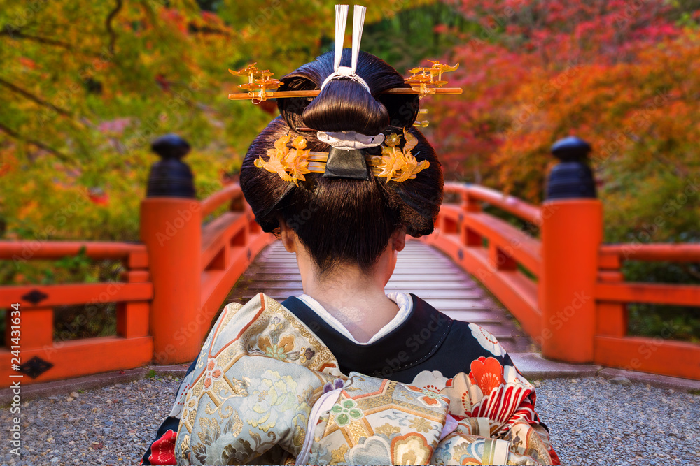 Fototapeta premium Kobieta w tradycyjnym kimonowym odprowadzeniu przy kolorowymi klonowymi drzewami w jesieni, Japonia
