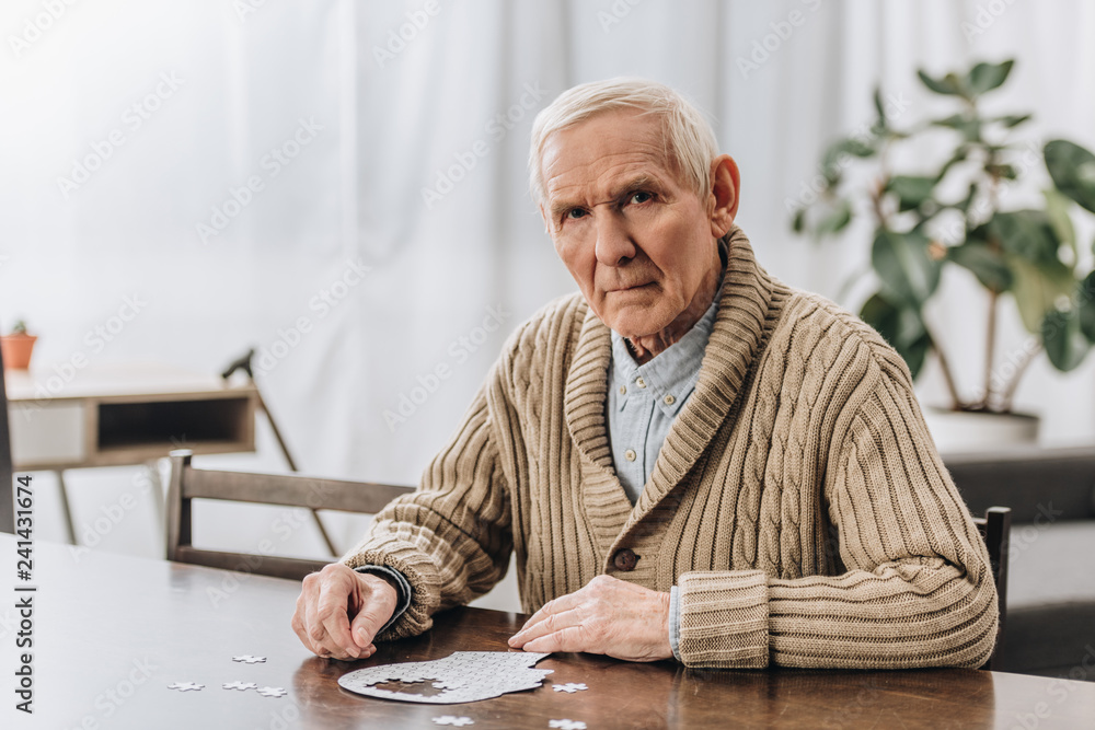 sad pensioner with grey hair playing with puzzles at home sad pensioner with grey hair playing with puzzles at home