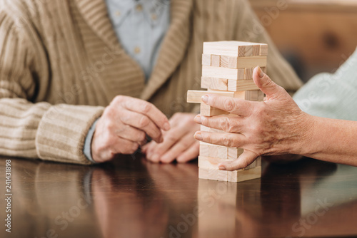 cropped view of senior couple playing jenga at home