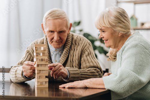 retired husband and wife playing jenga game on table