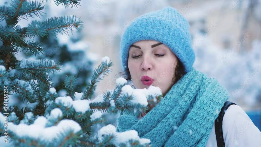 Girl blowing snow from christmas tree. Winter pastime concept Girl blowing snow from christmas tree. Winter pastime concept