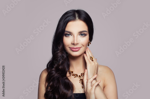 Fashion woman portrait. Girl with gold necklace, ring and earrings with amber on pink