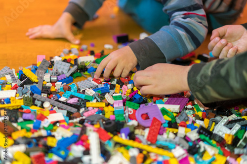 Close up of colorful plastic bricks on the floor. Early learning. Developing toys. Children s plastic constructor on the floor. Children s hands play a little constructor