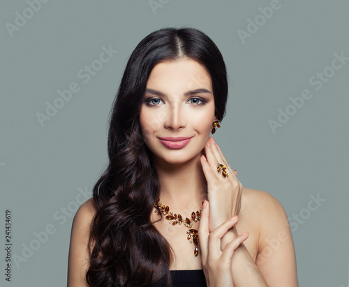 Pretty young woman with curly hair, makeup and gold ring, necklace, earrings with amber