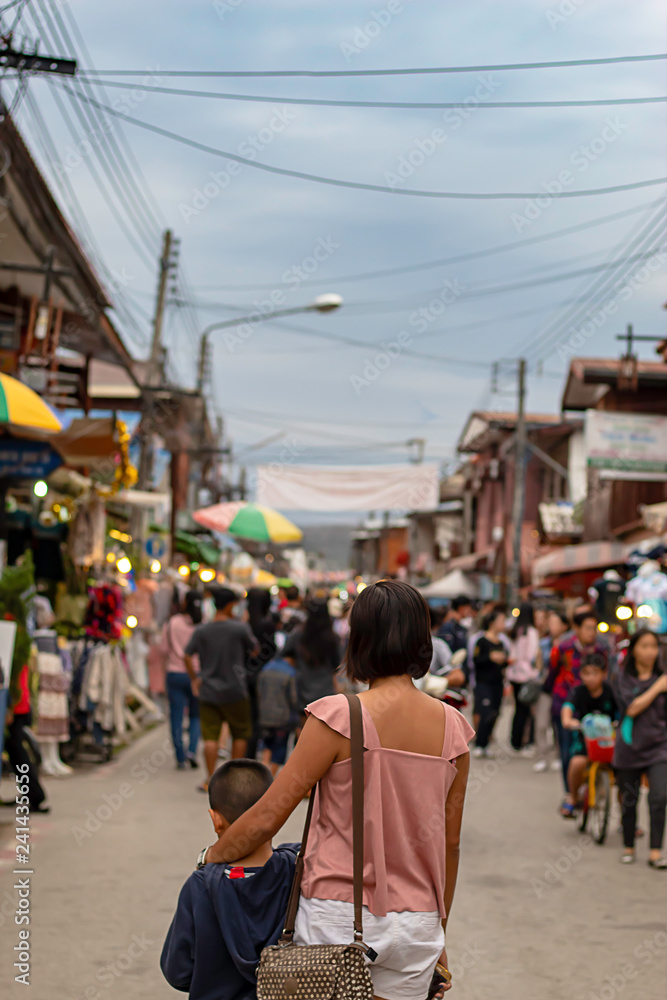 Mother and son on the street and blurry tourists at Walking Street Chiang Khan, Loei in Thailand.