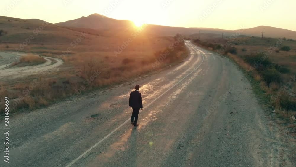 Man in suit walking away by the road