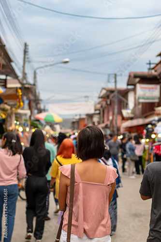Woman on the street and blurry tourists at Walking Street Chiang Khan, Loei in Thailand.