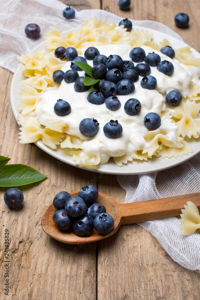 Tasty pasta with fresh organic blueberries and vanilla cream. Sweet dinner on retro wooden table. Tasty pasta with fresh organic blueberries and vanilla cream. Sweet dinner on retro wooden table.