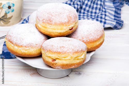 Traditional Polish donuts with powdered sugar on wooden background. Tasty doughnuts with jam.