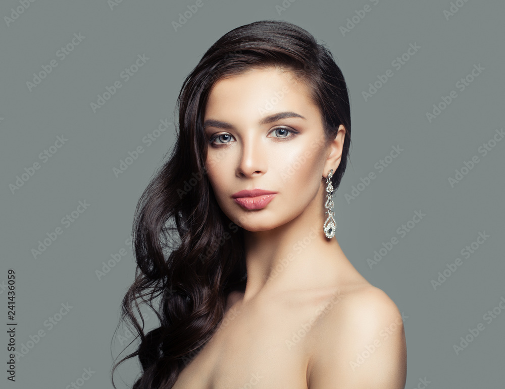 Healthy female face. Girl with long curly hair, makeup and diamond earrings