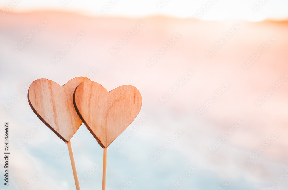 Fototapeta premium Two wooden hearts in orange sunset light