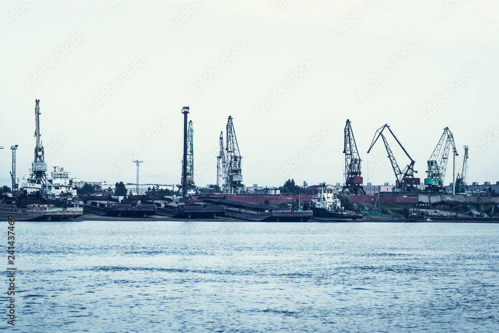 A barge in the river port and working cranes on the city background A barge in the river port and working cranes on the city background