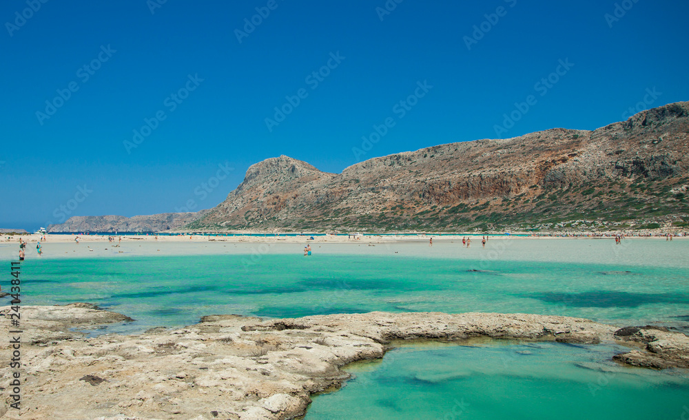 Balos lagoon on Crete island in Greece. Tourists relax and bath in crystal clear water of Balos beach.