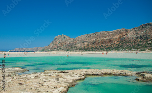 Balos lagoon on Crete island in Greece. Tourists relax and bath in crystal clear water of Balos beach.