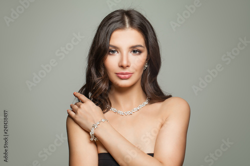 Glamorous jewelry model. Perfect brunette woman with makeup, long hair and diamond necklace and earrings portrait