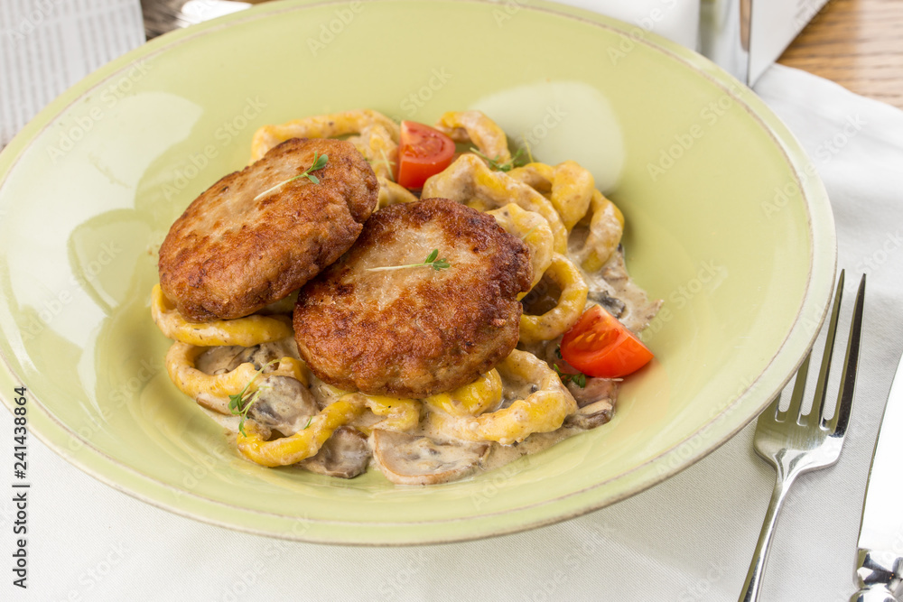 Meat patties with mushrooms and spaghetti on white textile table