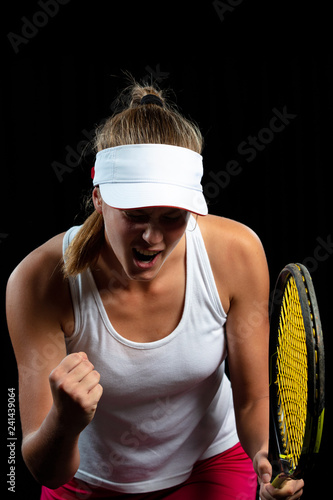 Beautiful girl tennis player with a racket on dark background wiht lights celebrating flawless victory © FS-Stock