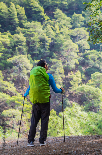 Peaceful person in harmony with nature. Anonymous man with a hiking bag and trekking poles in the mountains.