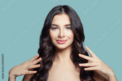 Young pretty woman with long healthy hair and natural makeup on blue background. Happy brunette girl, hair care and beauty salon background