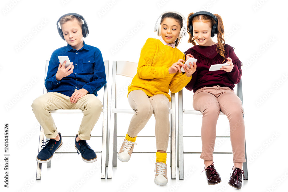 Obraz premium schoolgirl showing smartphone screen to friend quietly from boy sitting nearby isolated on white
