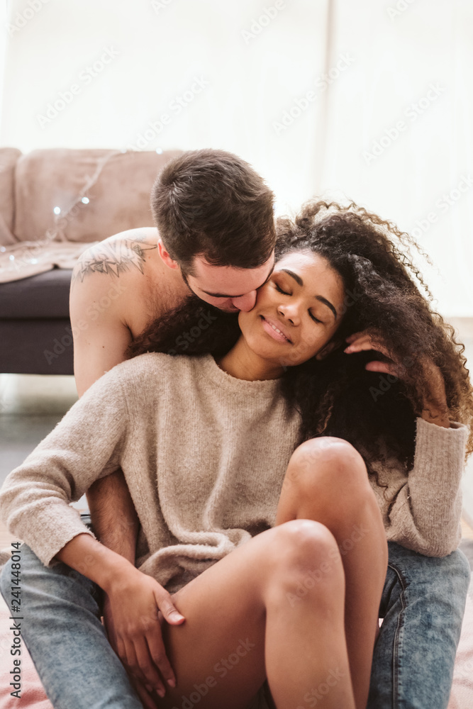 Multiethnic couple hugging on floor at home