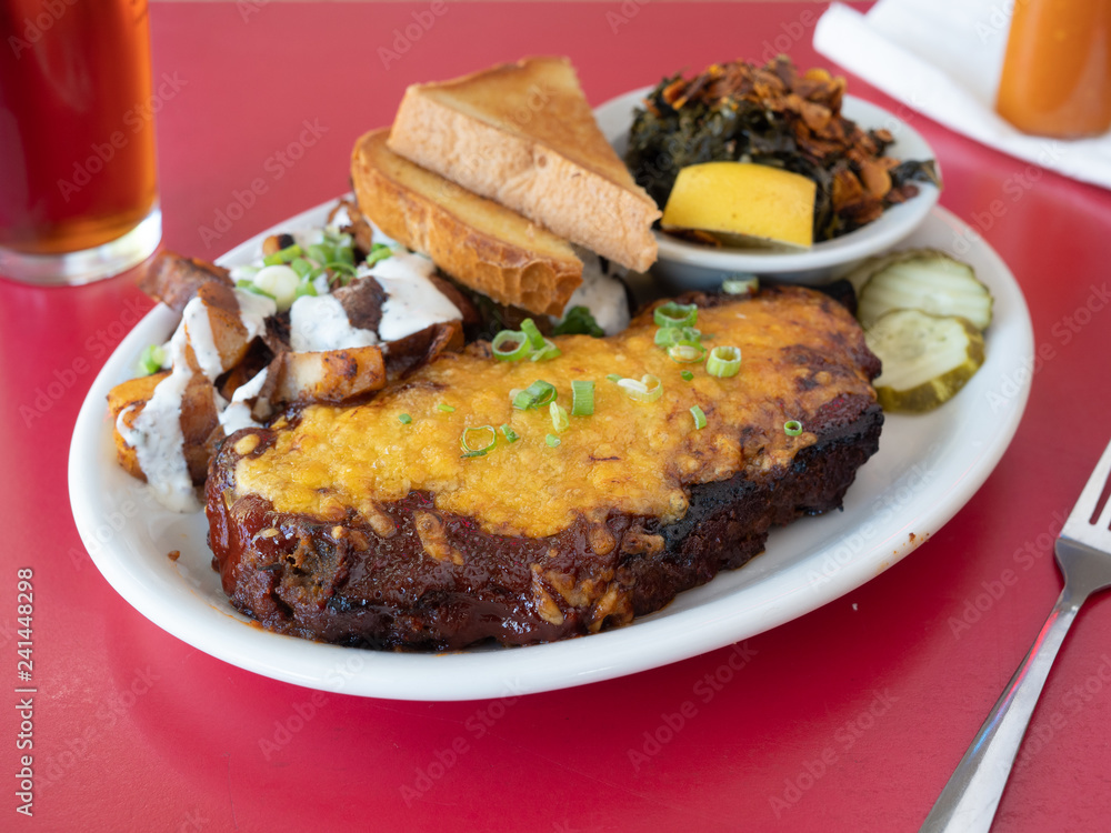 Vegan meatloaf topped with vegan cheese and served with Texas toast and collard greens. An atypical vegan dish.
