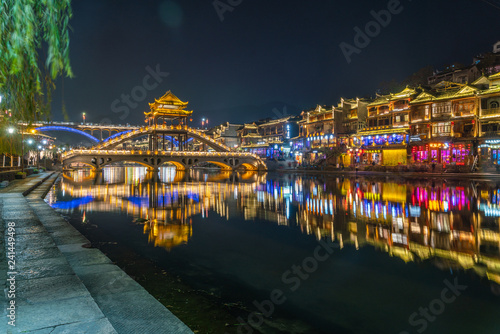 Colorful bridge reflected in water at night, Fenghuang ancient town