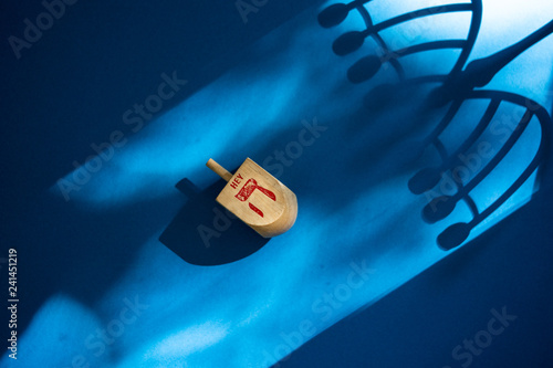 Wooden dreidel on colorful background with shadow of menorah. A fun Jewish game played during Chanukah photo