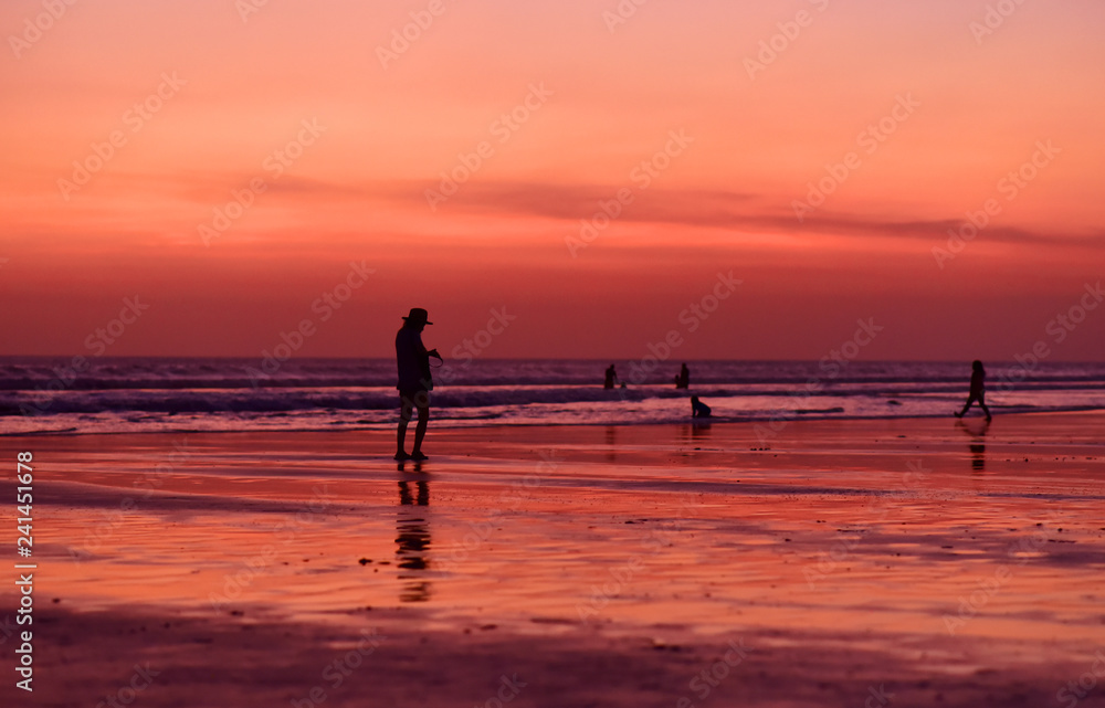 Tourist girl walking at Kuta Beach at sunset in Bali Island, Indonesia