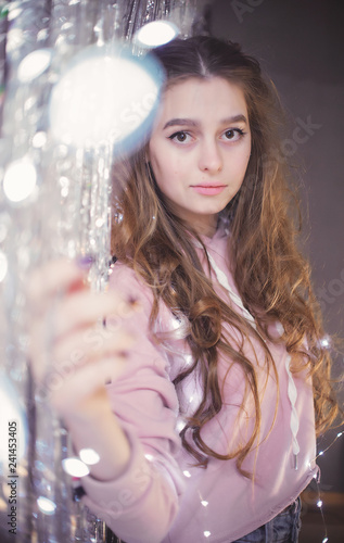 gentle and beautiful young girl on the background of garlands and tinsel