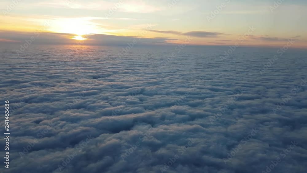 Aerial shot of fluffy clouds from a plane window at splendid sunset in summer  