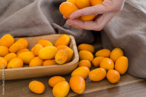 many fresh orange  kumquat a tropical fruit for sale at greengrocer store. Kumkuat and wicker bag from Turkey. photo