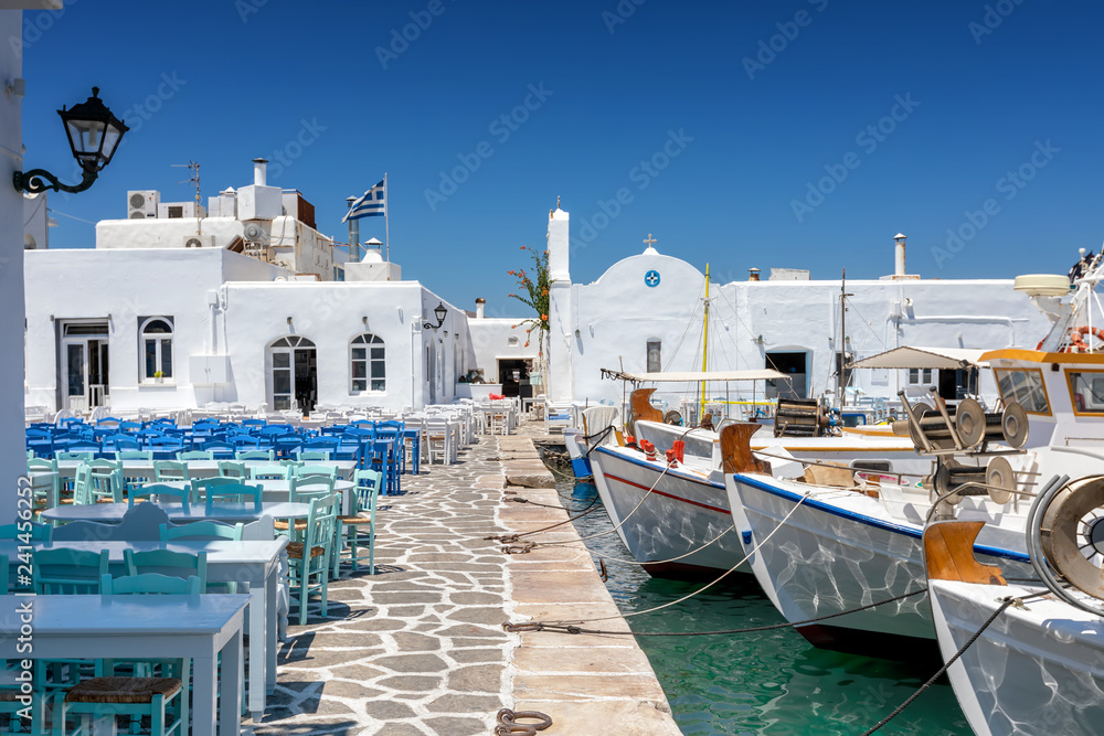 Fototapeta premium Promenada portowa z restauracjami i tawernami tuż obok łodzi rybackich w Naousa, Paros, Cyklady, Grecja