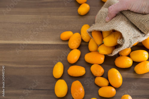 many fresh orange  kumquat a tropical fruit for sale at greengrocer store. Kumkuat and wicker bag from Turkey. photo