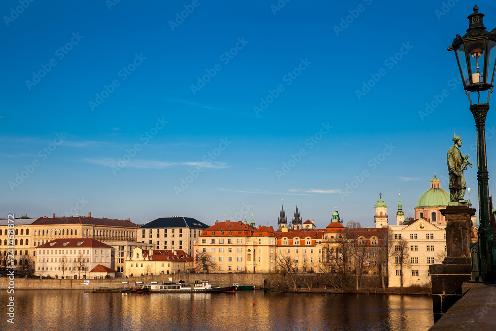 Obraz premium Boat on Vlava river at sunset in Prague seen from the iconic Charles Bridge