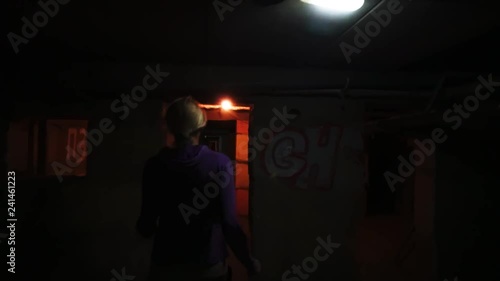 Woman running away from pursuer in dark gloomy basement corridor