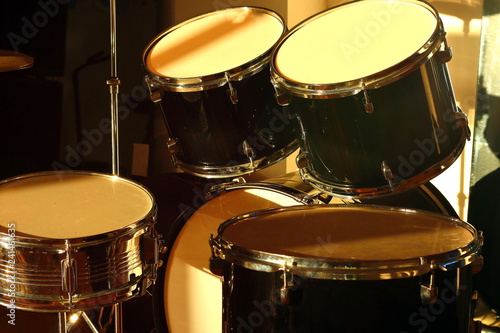 Drum set illuminated by the rays of the setting sun in a music studio. Closeup.