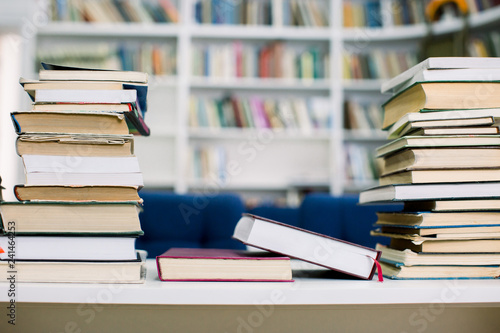 Stacks of paperback books  closeup  with the full bookshelf in the background. Searching for the right book in a bookstore. Piles of bestsellers.